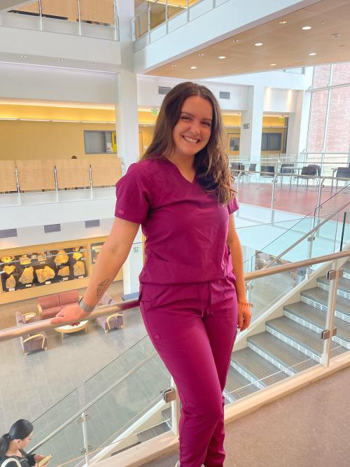 a student stands in the science center with a staircase behind